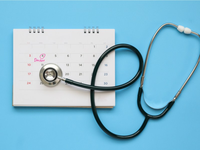 Stethoscope with calendar page date on blue background doctor appointment medical concept