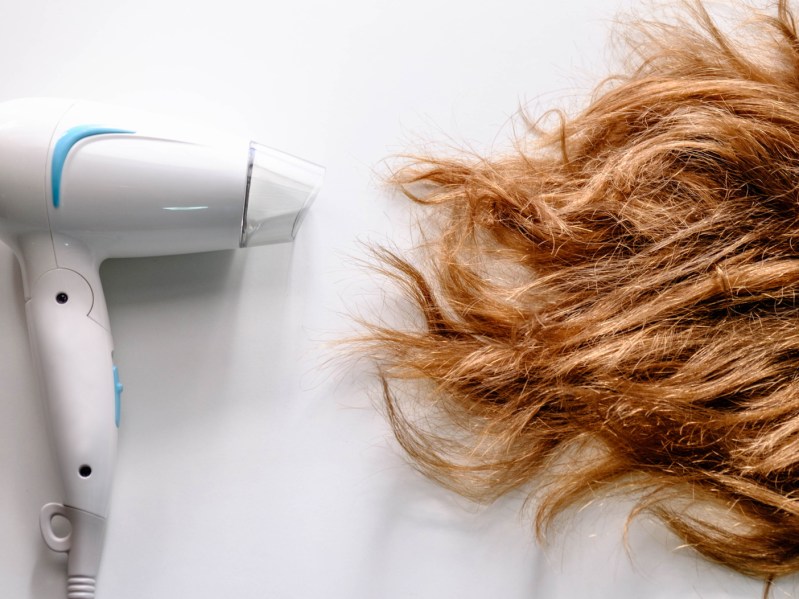 Hair dryer and damaged hair on a white background