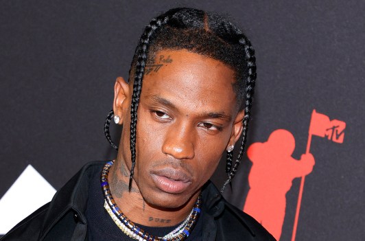 Travis Scott looking serious at a red carpet event.