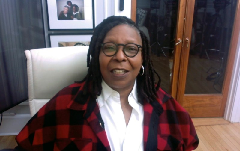 Whoopi Goldberg wears a red plaid jacket while giving remarks in a virtual format