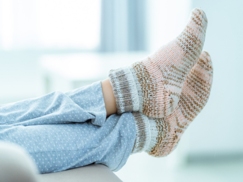 Person wearing fuzzy socks kicking feet up on couch