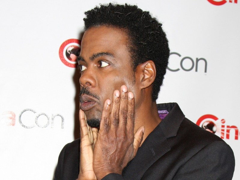 Chris Rock looking off-camera holding his face