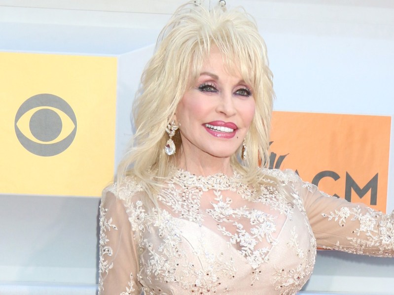 Dolly Parton wears a cream colored, semi sheer dress on the red carpet
