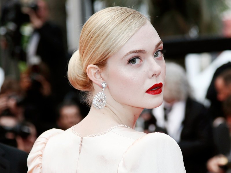 Elle Fanning looking over her shoulder at the camera, wearing white dress