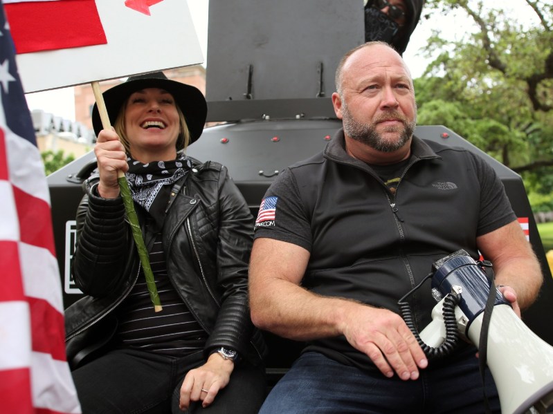Erika Wulff Jones and Alex Jones sit atop a vehicle during a protest