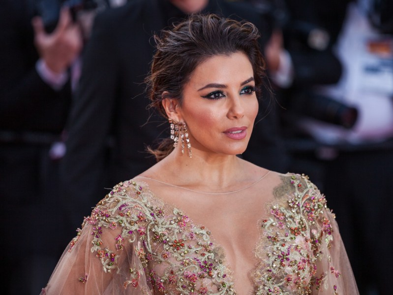 Eva Longoria looking off-camera wearing a gold dress