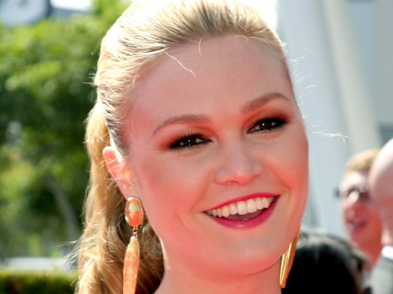 Close-up of Julia Stiles smiling with hair pulled back and gold earrings