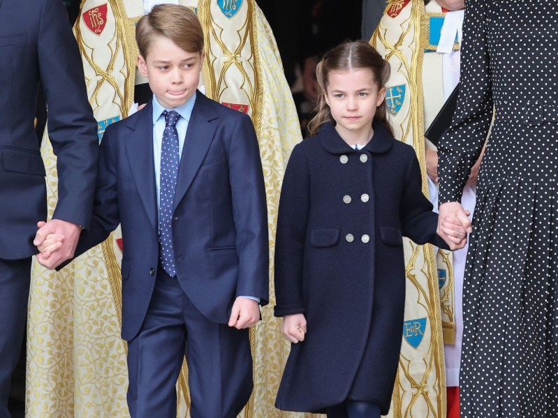 Prince George (L) and Princess Charlotte (R) holding hands and wearing navy blue
