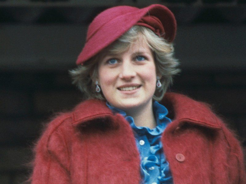 Princess Diana smiling and wearing red coat and hat