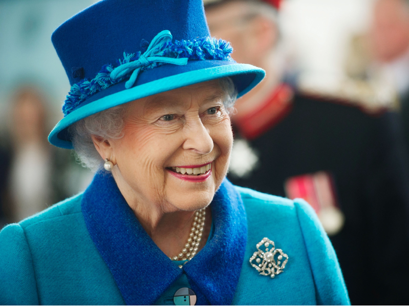 Queen Elizabeth smiling in blue hat and suit