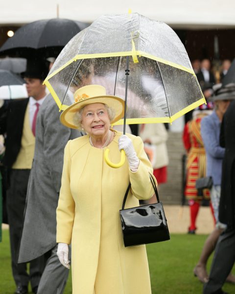 Queen Elizabeth wearing pale yellow and holding an umbrella