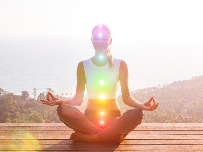 Woman in lotus position with chakras illuminated