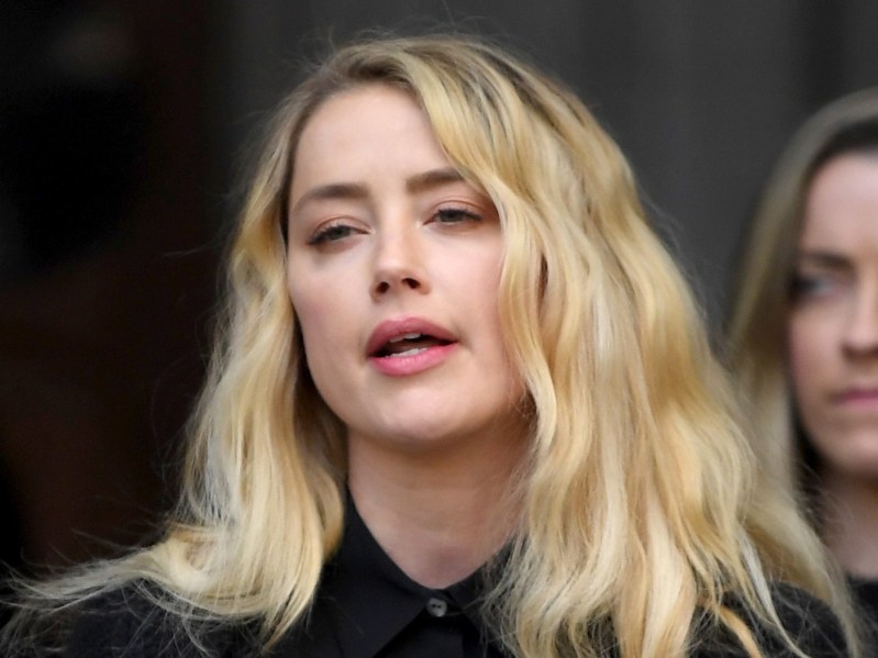 Closeup of Amber Heard wearing black button-down speaking to press