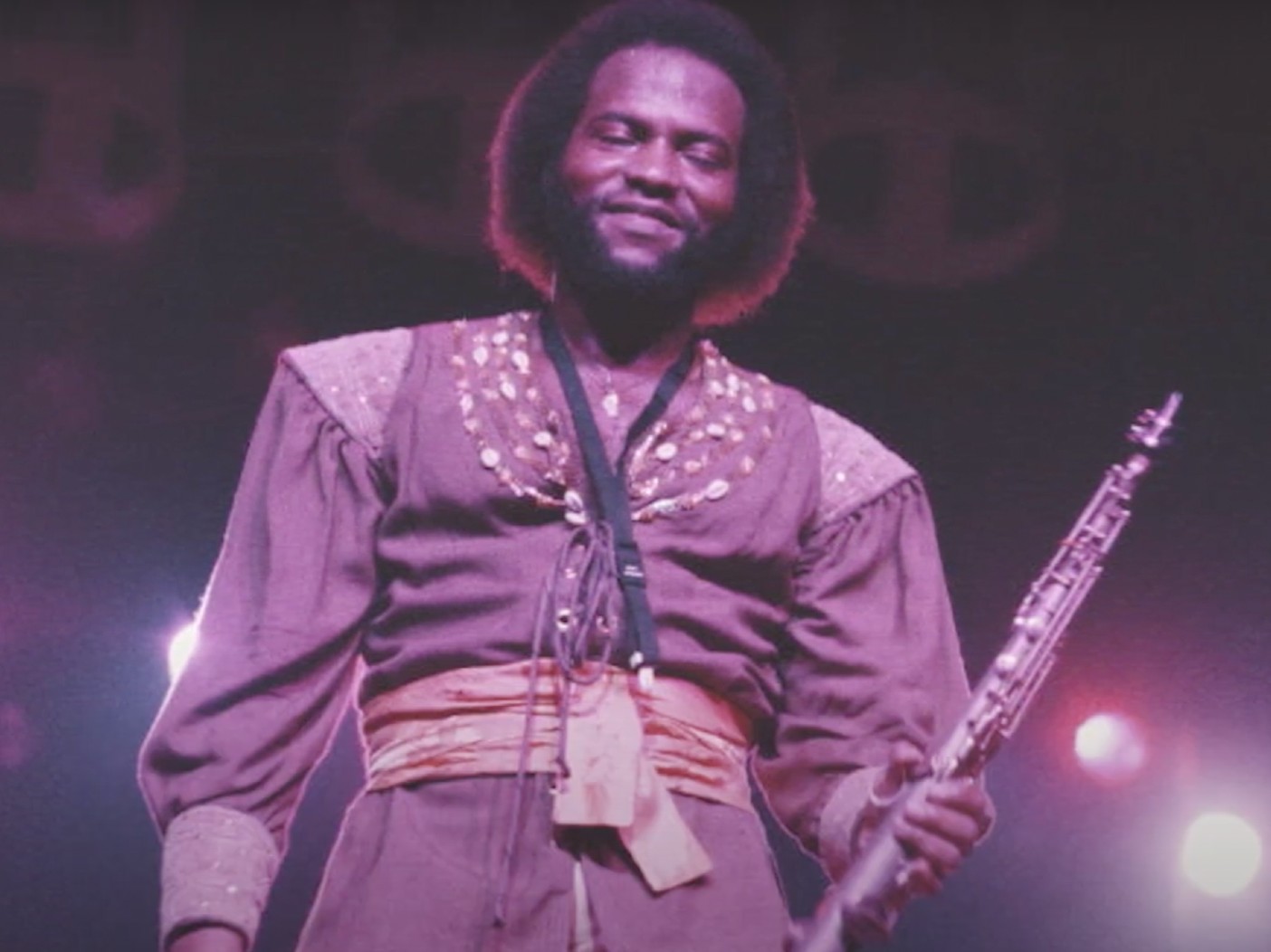 Andrew Woolfolk smiling onstage holding saxophone