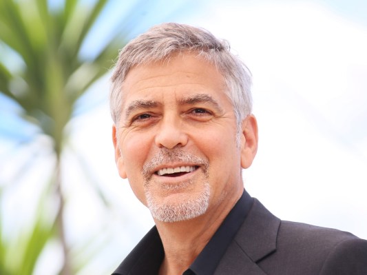 Closeup of George Clooney smiling outdoors wearing black top