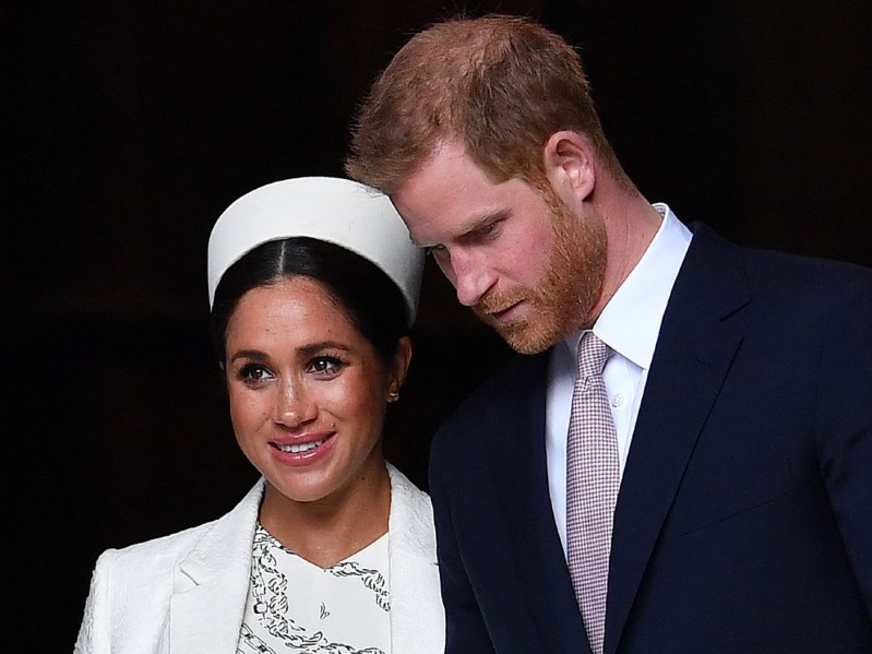 Meghan Markle (L) wearing a white outfit and Prince Harry (R) wearing a suit and tie
