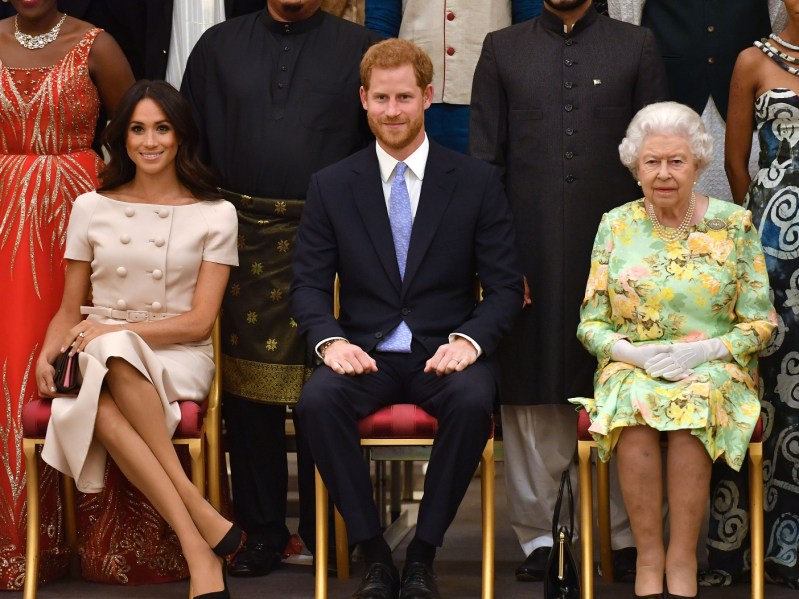 (From left to right): Meghan Markle, Prince Harry, Queen Elizabeth, all sitting in chairs