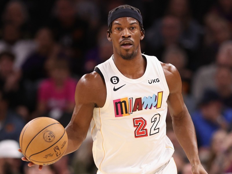 Jimmy. Butler dribbles a basketball while wearing a white Miami Heat jersey
