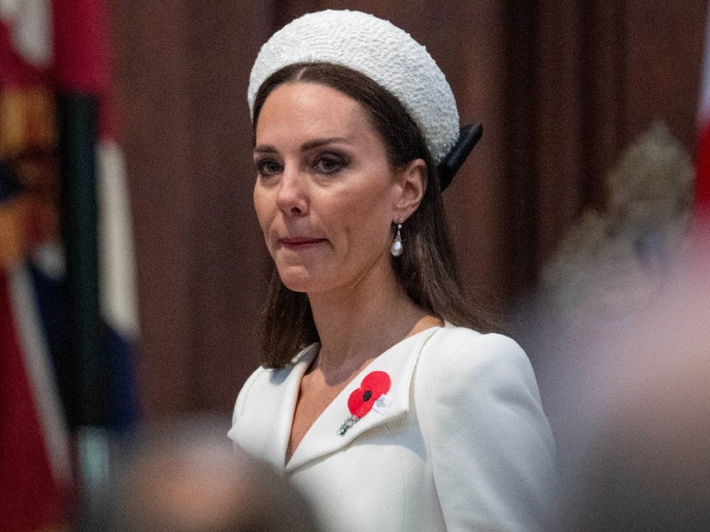 Kate Middleton wears a white suit and hat during a solemn royal event