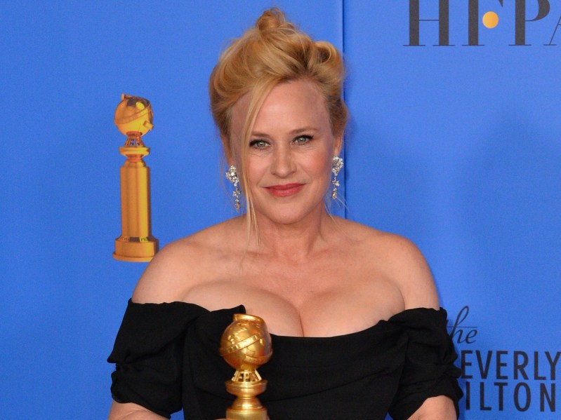 Closeup of Patricia Arquette wearing off-shoulder black dress and updo holding award