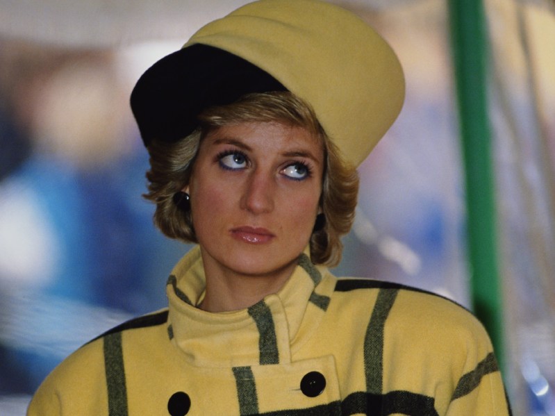 Princess Diana wears a yellow plaid coat and a black and yellow hat