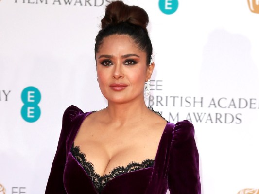 Salma Hayek wears a deep violet gown with lacy details on the red carpet