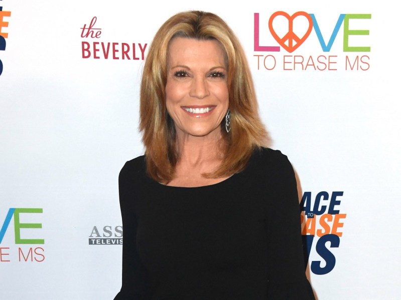Vanna White wearing long-sleeved black outfit, smiling in front of a white background