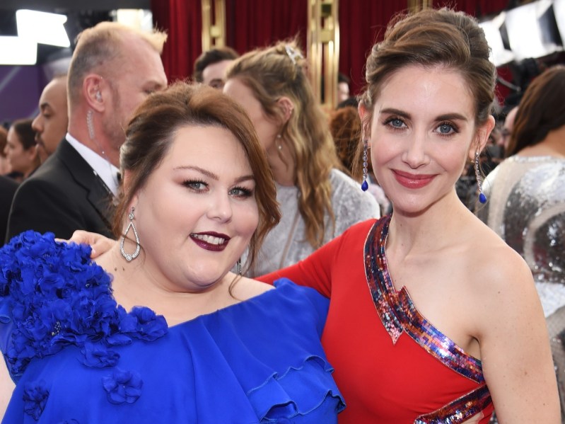 Chrissy Metz (L) wearing bright blue dress and Alison Brie R) wearing one-shouldered red dress