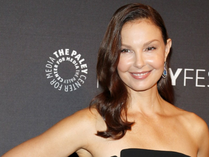 Ashley Judd wears a black strapless dress against a gray background on the red carpet