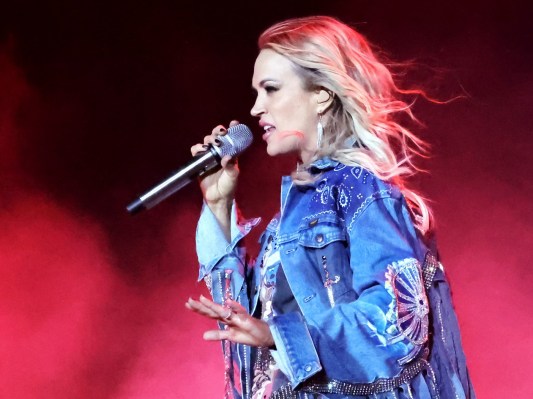 Carrie Underwood wears a blue jean jacket onstage as she performs