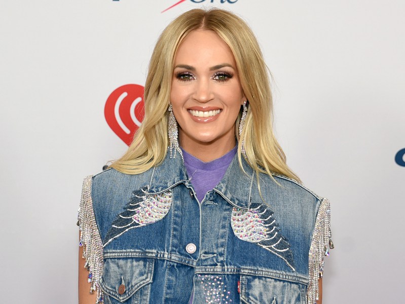 Carrie Underwood smiling in a denim vest
