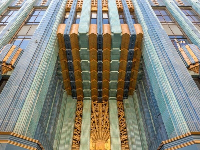 The exterior of a tall building is shown. The design consists of vertical stripes of various shades of blue with an accent of gold