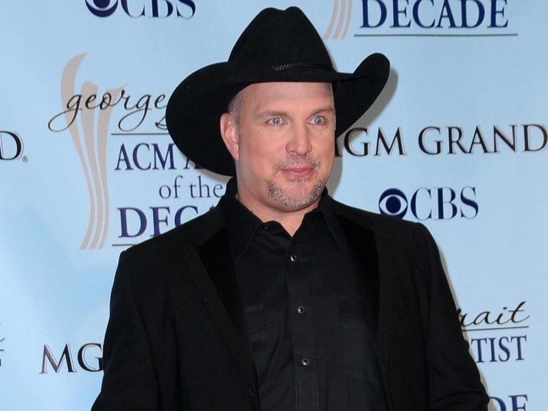 Garth Brooks posing on red carpet wearing all-black outfit and black cowboy hat