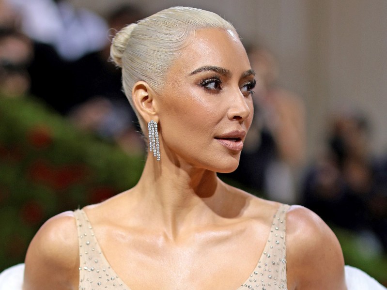 Kim Kardashian looking off to the right of the camera. She is wearing a sequined dress and her bleached hair is pulled back into a tight bun.