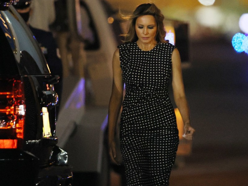 Melania Trump looking down and walking. She is wearing a black and white polka-dotted jumpsuit