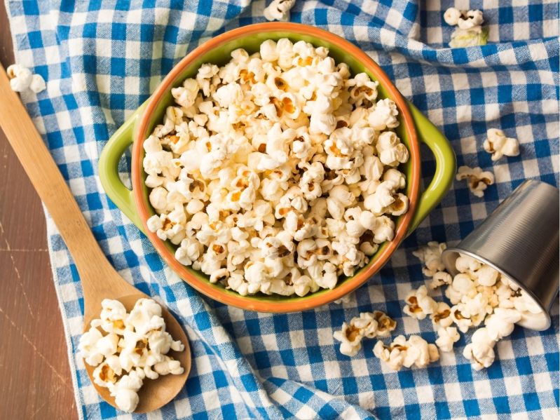 A bowl of popcorn styled on a blue checked tablecloth