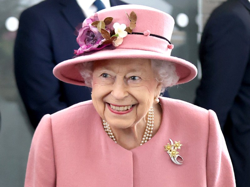 Queen Elizabeth smiles in a baby pink top and hat