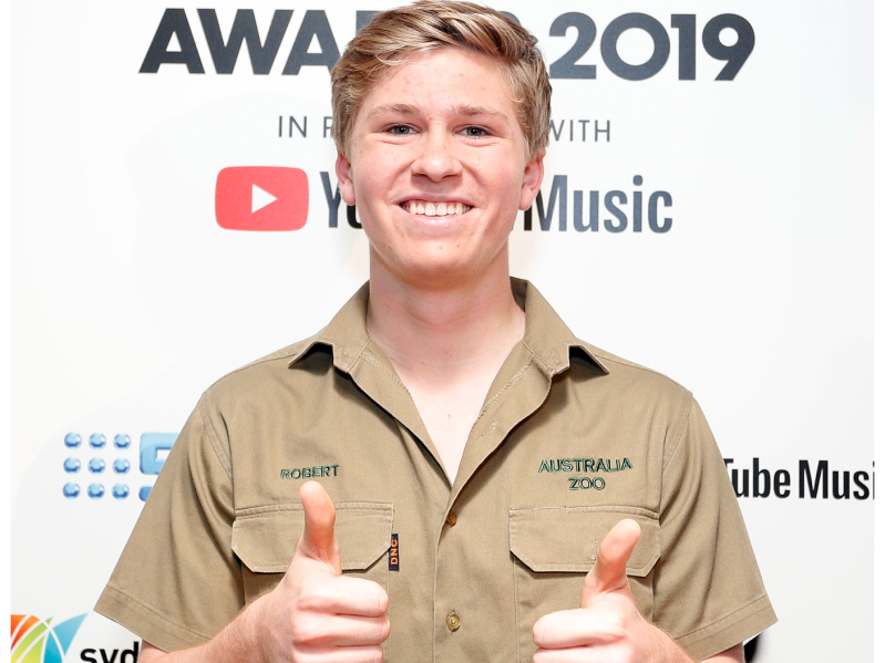 Robert Irwin gives a thumbs up and a smile while wearing an "Australia Zoo" shirt