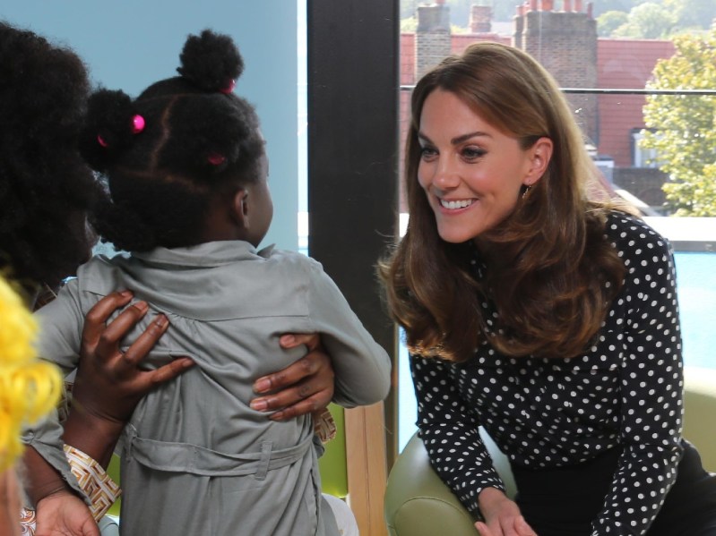 Kate Middleton wears a black blouse with white dots during a royal charity visit