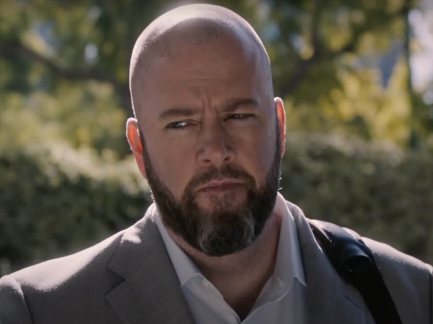 Toby from "This Is Us" has a suspicious look on his face. He is standing outside and looking off to the left