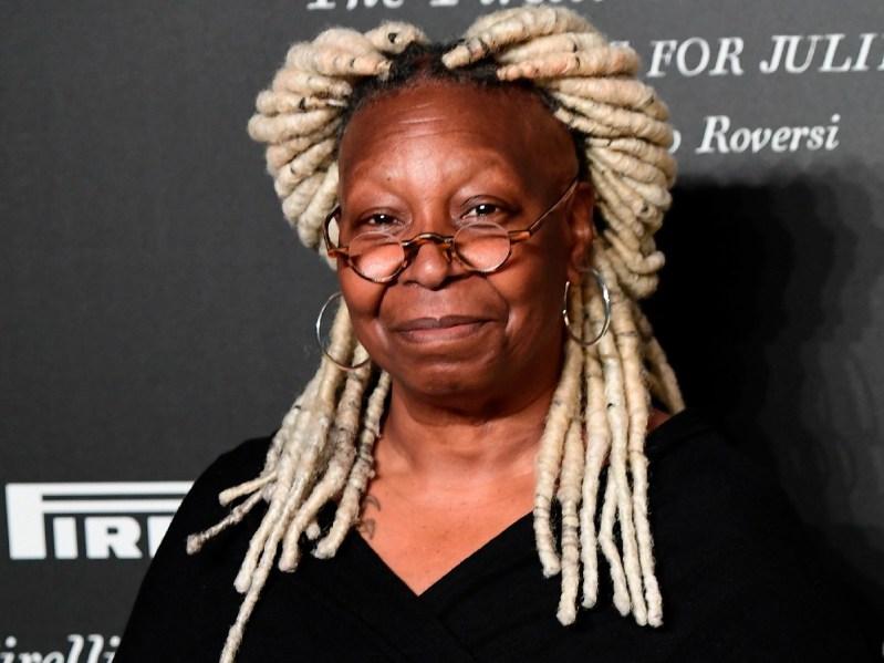 Whoopi Goldberg wears a black top as she poses on the red carpet
