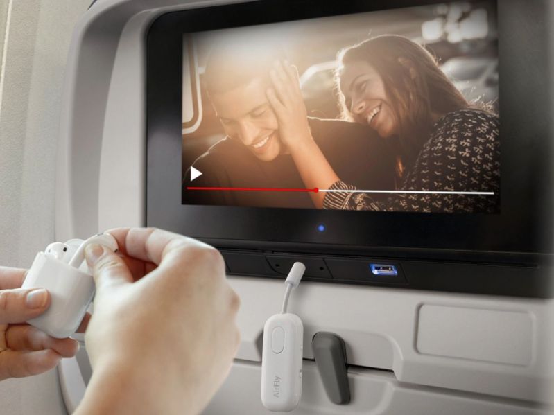 Hands pulling out ear phones to watch entertainment on plane using AirFly transmitter