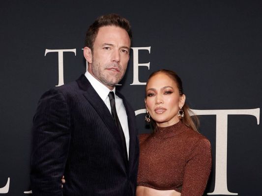 Ben Affleck in a navy suit with Jennifer Lopez in a brown dress