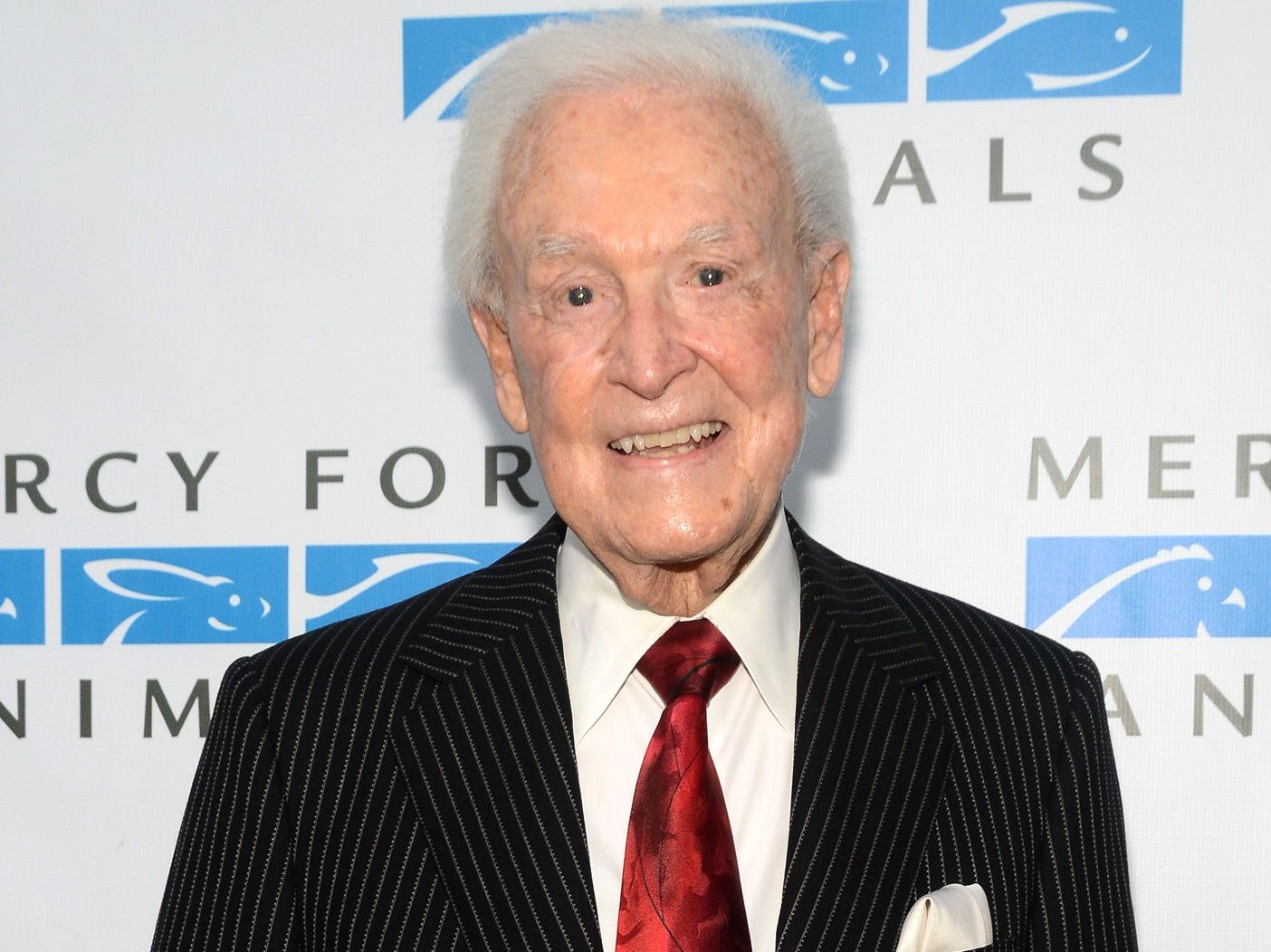 Bob Barker smiles wearing red tie with black blazer