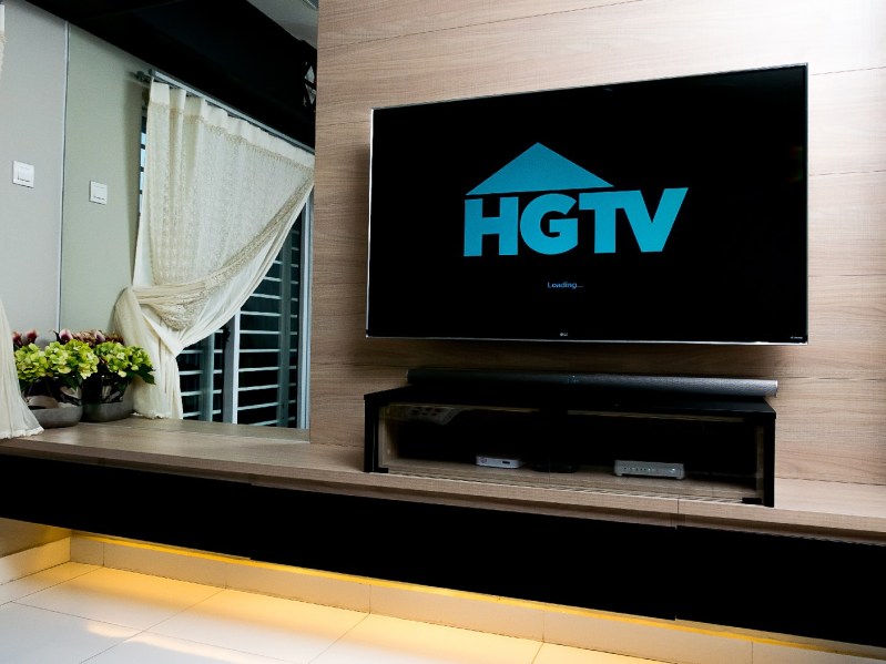 A TV in a home living room shows the HGTV logo