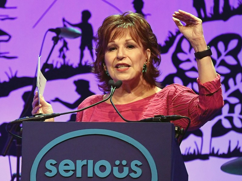 Joy Behar makes remarks onstage while wearing a red top
