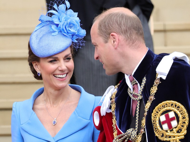 Kate Middleton (L) wearing powder blue top and matching hat, smiling at Prince William