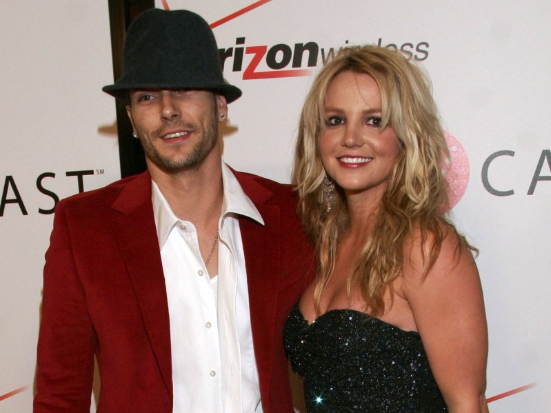 Kevin Federline (L) wearing red blazer over white shirt with black fedora, standing next to Britney Spears, who is wearing a strapless, sequined black dress