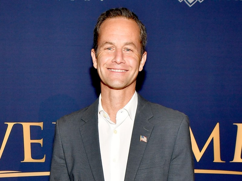 Kirk Cameron smiles in a white button-down shirt and navy blue blazer