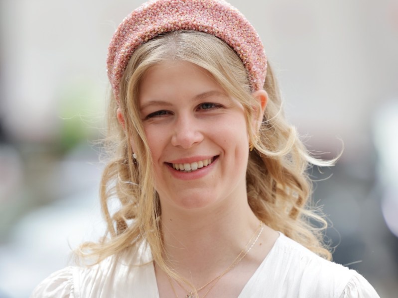 Closeup of Lady Louise Windsor wearing white smock dress and pink headband